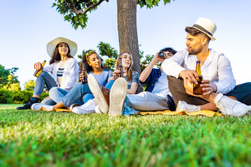 Group of five happy young diverse multiracial gen z people in outdoor party drinking beer from...