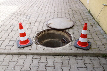 Offener Kanalschacht ist mit Leitkegel abgesichert