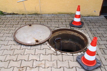 Offener Kanalschacht ist mit Leitkegel abgesichert