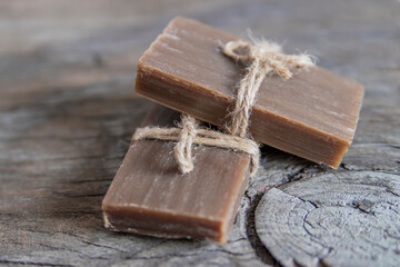 Two pieces of handmade soap tied with jute rope, vintage wooden background.