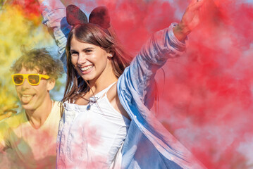 Beautiful young woman hold light up colored smoke bombs - Happy friends having fun in the park with multicolored fog bombs - Young students celebrating spring break together. Holi festival concept.