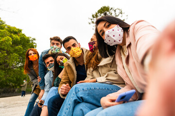 Selfie of young smiling people having fun together wearing face mask - Happy friends group taking selfie in park at european trip - Young people addicted by sharing stories on social network community