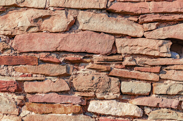 Old vintage stone wall made of untreated red stone