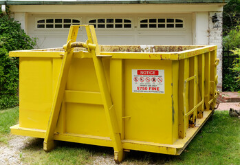 Yellow industrial dumpster in residential neighborhood.