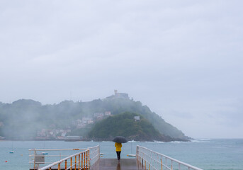 Naklejka premium Woman in the rain on a jetty in the city of Donostia-San Sebastian, Euskadi