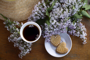 straw hat, coffee cup, lilac bouquet, heart-shaped cookies. romantic breakfast. with love. still life with flowers.