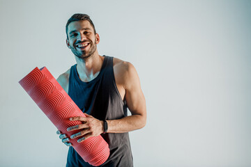 Smiling sportsman hold fitness mat in studio
