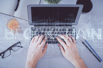 Double exposure of man's hands typing over computer keyboard and crypto currency theme hologram...