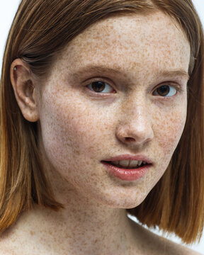 Close up portrait of girl in freckles in the studio on white background with natural makeup