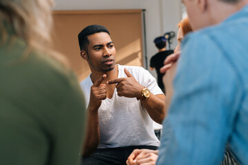 Front view of African American male leader explaining new strategies to young creative business team, during brainstorming in meeting room. Businessman discussing work with team in boardroom.