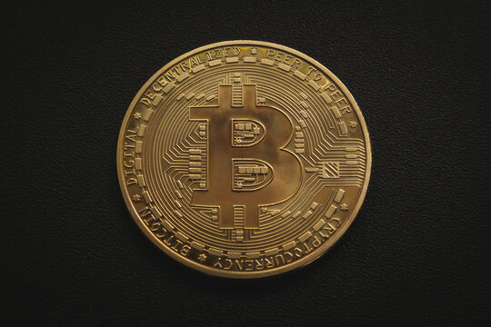 Gold Bitcoin coin on a black surface close up. Soft focus