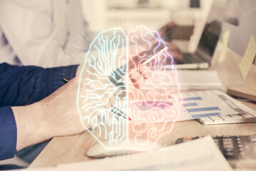 Double exposure of man's hand holding and using a digital device and brain hologram drawing. Data...