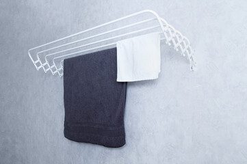 White metal wall-mounted clothes dryer with towels on gray wall background.