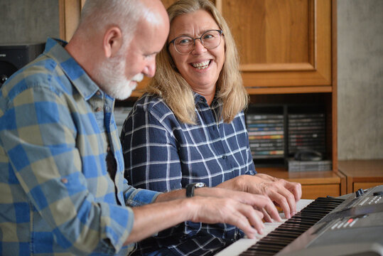 Attractive couple playing an electric piano at home