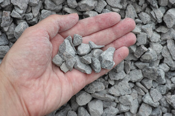 A man holding a heap of crushed granite in his palm - obrazy, fototapety, plakaty