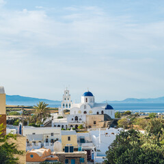 Fototapeta na wymiar Cityscape of traditional village Karterados on Santorini island, Greece. Traditional white architecture. View of the Greek Orthodox church with a blue domes and bell tower.