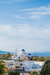 Cityscape of traditional village Karterados on Santorini island, Greece. Traditional white architecture. View of the Greek Orthodox church with a blue domes and bell tower.