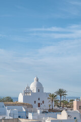 Cityscape of traditional village Karterados on Santorini island, Greece. Traditional white architecture. View of the Greek Orthodox church with bell tower.
