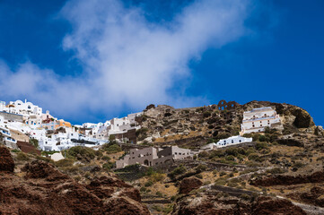 Fototapeta na wymiar View from sea of Oia up the hill. Santorini, Greece. White city architecture. Luxury tourism. Stairs on the rock.