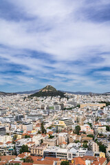 Cityscape of Athens from above. Urban architecture. Mount Lycabettus. Cloudy sky. Summer day. Tourism in Europe.
