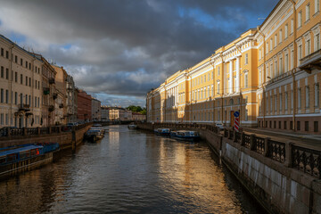 Moika River embankment and view of the eastern wing of the General Staff building on a sunny summer day with clouds, Saint Petersburg, Russia