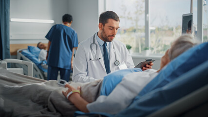 Obraz premium Hospital Ward: Friendly Doctor Talks to Beautiful Senior Female Patient Resting in Bed, Explains Test Results, Gives Recovery Advice. Physician Talks to Old Lady Recovering after Successful Surgery