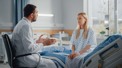 Hospital Ward: Sitting on Bed Caucasian Female Patient Listens to Experienced Doctor who Explains...