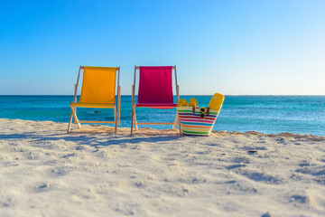 Beach chairs with beach bag on the shoreline at sunset, beautiful beach