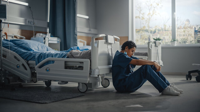 Hospital Intensive Care Coronavirus Ward: Portrait Of Sad, Tired Black Nurse Taken Off Face Mask Sitting On A Floor, Sorry For All The Patients Lost To Pandemic. Brave Hero Paramedics Save Lives