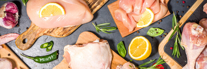 Various raw chicken meat portions. Set of uncooked chicken fillet, thigh, wings, strips and legs on black cooking table background with spices