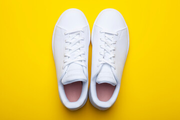Pair of casual shoes on yellow background. Top view of stylish sneakers on color background