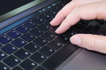 Closeup of hand typing on a laptop notebook PC computer english language keyboard which finger is on touch type keyboard button location.