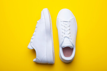 Pair of casual shoes on yellow background. Top view of stylish sneakers on color background - obrazy, fototapety, plakaty