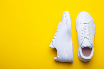 Pair of casual shoes on yellow background. Top view of stylish sneakers on color background with place for text - obrazy, fototapety, plakaty