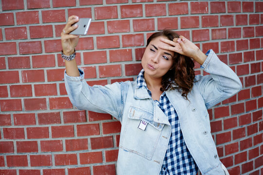 Female tourist with duck face and v sign clicking selfie images during free time in city, millennial hipster girl using smartphone front camera for shooting influence video about youth lifestyle