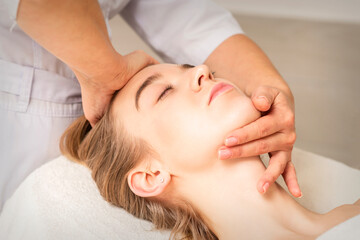 Obraz na płótnie Canvas Young caucasian woman receiving a head and chin massage in a spa medical center