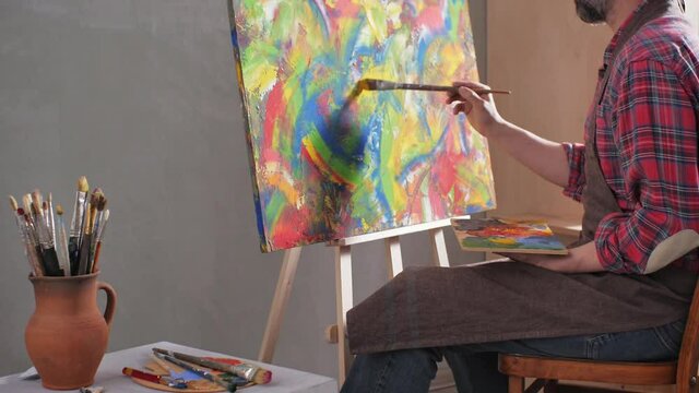 Male artist working on painting. Man artist painter in creative studio as art concept