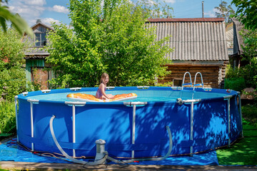 Cute little girl swims on beach air mattress in the pool