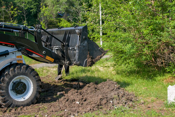 Earthworks in the city park. Unloading and leveling the ground for the lawn. Excavator work and...