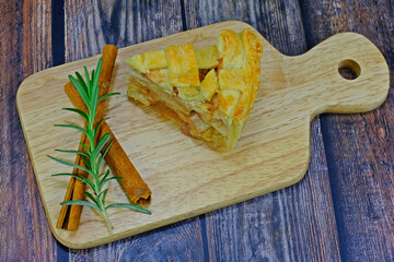 Homemade delicious apple pie slice served on wooden tray.