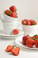 Blurred image of strawberries in a white plate, cup, saucer. Still life with strawberries.