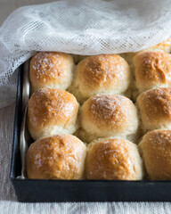 Homemade bread rolls with sugar in baking tin mold on linen tablecloth. Close-up, selective focus