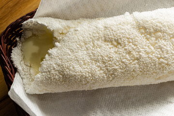 Uma tapioca dentro de uma cesta de vime sobre superfície de madeira.