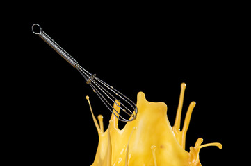Wire whisk with Egg splash isolated on black background, motion action.