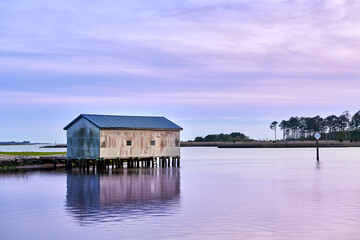 A boat house on a creek just after sunset with a purple sky