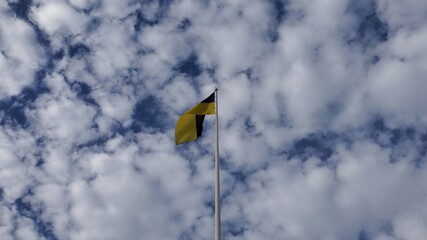 Ukrainian flag waves in wind on cloudscape background at sunny day. Yellow and blue flag of Ukraine country. Fluffy white cumulus clouds in blue sky