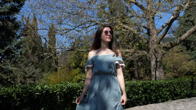 Pretty smiling woman in a stylish outfit walks confidently through the park. Joy of life, active lifestyle, fashion blogger, catwalk