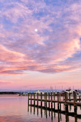 Fototapeta na wymiar The moon in a cotton candy sunset with a dock in the foreground 