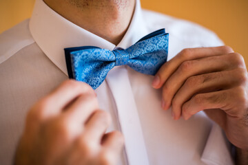 Detail on a blue bow tie during the groom's preparations for a wedding, or a gentleman for a ball or opera
