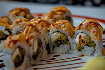 Sushi sashimi roll with various sauces and accoutrement plated professionally at a fancy asian luxury restaurant pickled ginger slices out of focus.